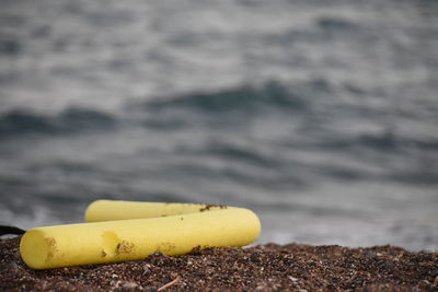Close-up of cigarette on land against sea