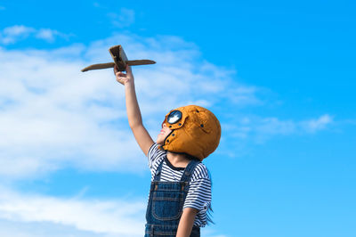 Low angle view of woman with arms outstretched against blue sky