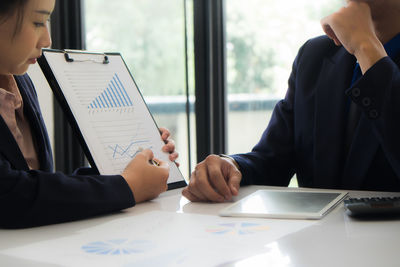 Midsection of woman holding camera on table