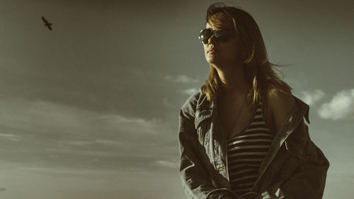 Young woman in sunglasses against sky