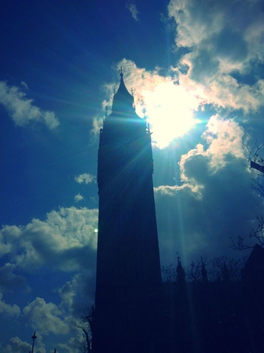 low angle view, sky, architecture, built structure, building exterior, cloud - sky, blue, sunbeam, sun, sunlight, silhouette, cloud, lens flare, religion, tower, spirituality, church, tall - high, place of worship