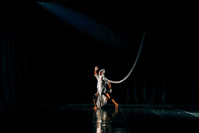 Full length of man standing on stage against black background