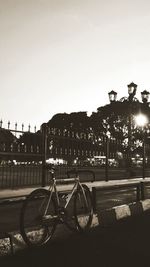 Bicycle by canal against buildings in city against clear sky