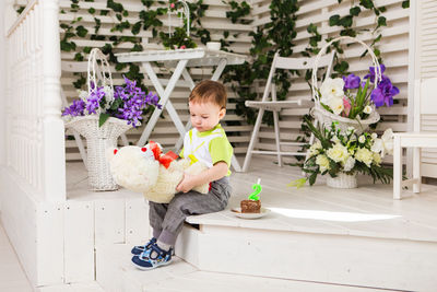Full length of boy with stuffed toy sitting outdoors