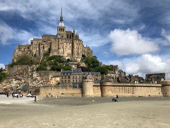 Low angle view of le mont-saint-michel against cloudy sky