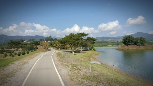 Road by trees against sky