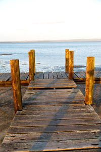 Wooden posts in sea against clear sky