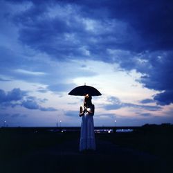 Woman standing with umbrella against blue sky