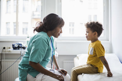 Female pediatrician looking at mischief boy in clinic