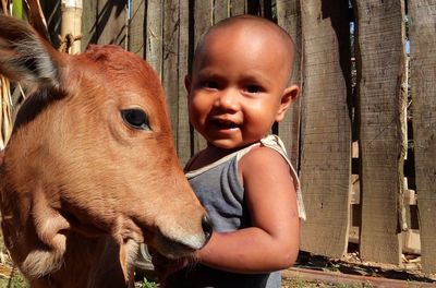 Portrait of baby girl standing by calf