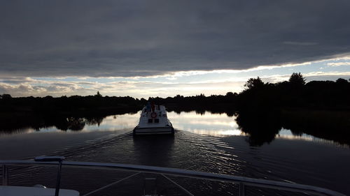 Silhouette boat in river against sky during sunset