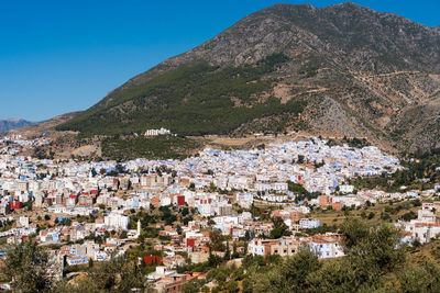 Aerial view of townscape and mountains against clear sky