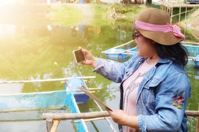 Young woman using mobile phone while looking at camera