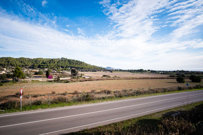 Road amidst field against sky