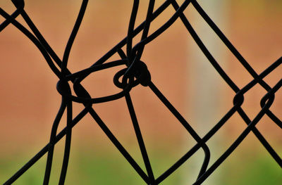 Close-up of chainlink fence against sky during sunset