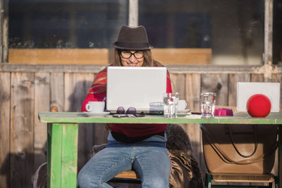 Smiling of woman using laptop while sitting at table