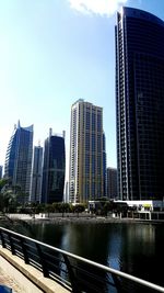 Modern buildings by river against sky in city