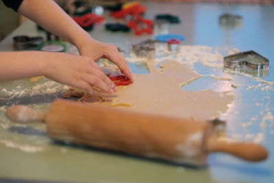 Cropped hand of person preparing gingerbread cookies on table