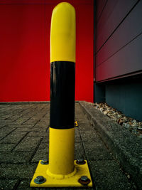 Close-up of yellow metal pole against wall