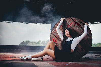 Portrait of young woman leaning on wooden table while sitting on floor