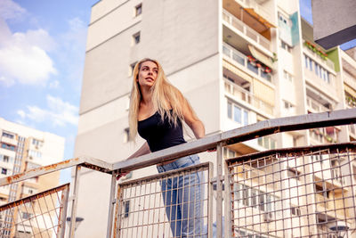 Low angle view of young woman standing by railing