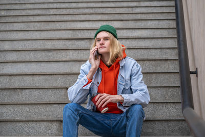 Young man using mobile phone while sitting on staircase