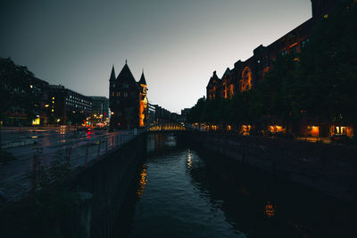 Illuminated buildings by river at night