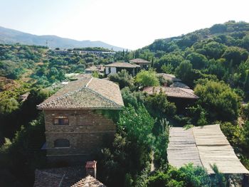 Houses by trees and mountains against sky