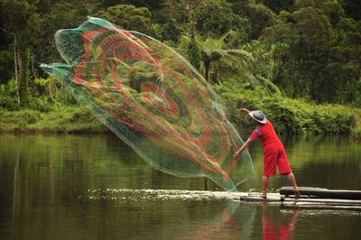 Fisherman casting net on lake