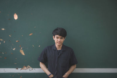 Portrait of young man standing against wall