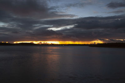 Scenic view of sea against dramatic sky during sunset