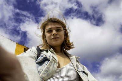 Portrait of woman doing selfie against sky