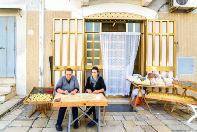 Portrait of a young couple sitting in front of building