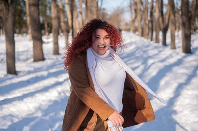 Portrait of young woman standing on snow covered field