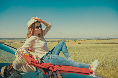 Side view of young woman sitting at beach