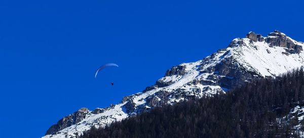 Low angle view of snowcapped mountain against blue sky