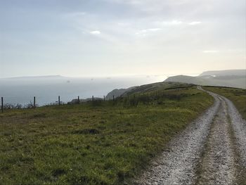 Panoramic view of road amidst field against sky