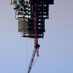 Cranes in city against clear sky