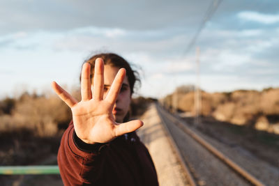 Midsection of man standing by railroad tracks against sky