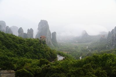 Landscape with rock formation and trees in fog 