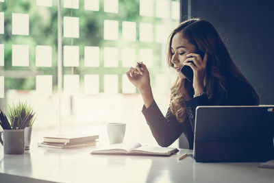 Businesswoman talking over smart phone while sitting in office