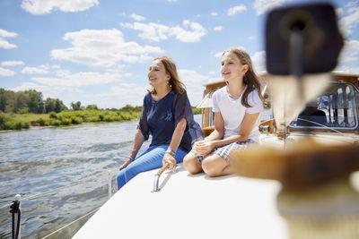 Happy grandmother sitting with granddaughter on boat deck