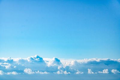 A desktop wallpaper image of fluffy white clouds and blue skies on the horizon