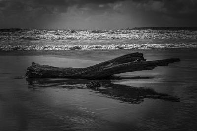 View of calm beach against cloudy sky