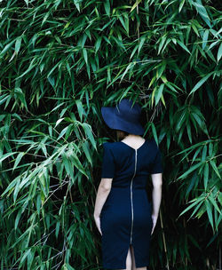 Rear view of woman wearing hat standing against plants