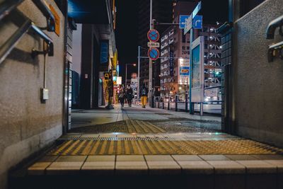 Illuminated street amidst buildings in city at night