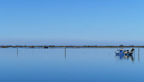 Fishing boat in sea against clear blue sky