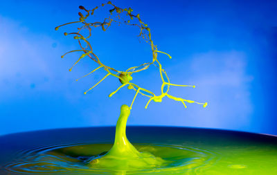 Close-up of water splashing on table against clear blue sky