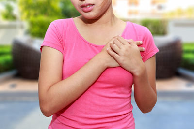 Midsection of woman with chest pain standing outdoors