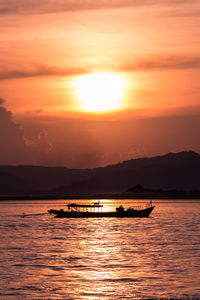 Silhouette boat in sea against orange sky